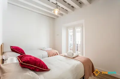 two beds in a room with red pillows at Buenos Aires by LiveWork in Cádiz