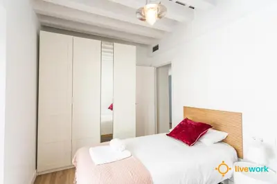a white bedroom with a large bed with red pillows at Buenos Aires by LiveWork in Cádiz