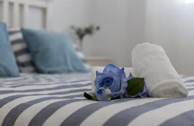 a bed with a rolled up towel and a blue flower at Laguna 3 Rooms Piscina in Chipiona