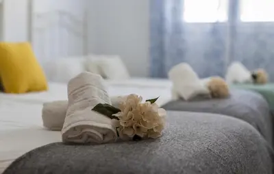 two towels on a bed with a flower on it at Laguna 3 Rooms Piscina in Chipiona