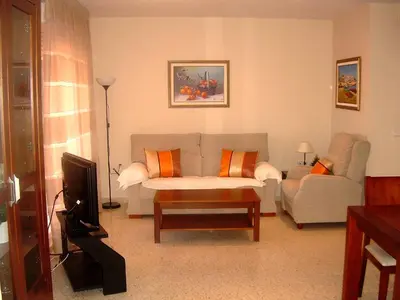 a living room with a couch and a tv at Apartamento JARDINES DE BAJO GUIA in Sanlúcar de Barrameda