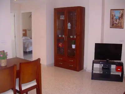 a living room with a television and a cabinet at Apartamento JARDINES DE BAJO GUIA in Sanlúcar de Barrameda