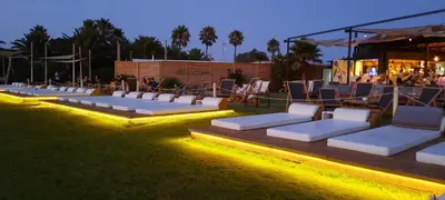 a row of white lounge chairs on a lawn at night at Apartamento JARDINES DE BAJO GUIA in Sanlúcar de Barrameda