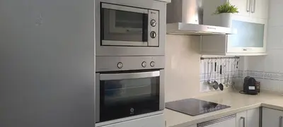 a kitchen with a stove and a microwave at Apartamento JARDINES DE BAJO GUIA in Sanlúcar de Barrameda