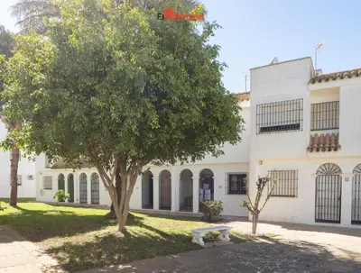a tree and a bench in front of a building at El Anfitrión - Casa Dunas in Sanlúcar de Barrameda