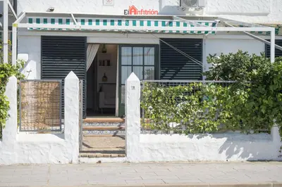 a white house with a gate and a porch at El Anfitrión - Casa Dunas in Sanlúcar de Barrameda