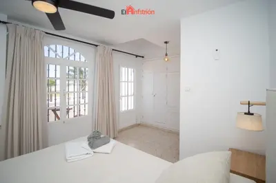 a white bedroom with a bed and a window at El Anfitrión - Casa Dunas in Sanlúcar de Barrameda