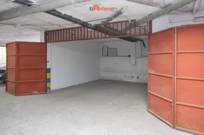 an empty garage with orange doors and a ladder at El Anfitrión - Casa Dunas in Sanlúcar de Barrameda