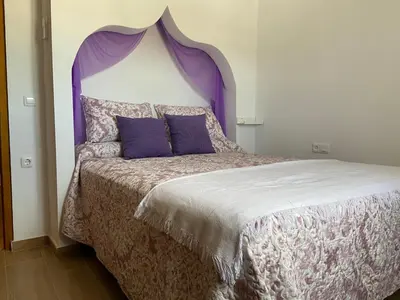 a bedroom with a bed with a purple headboard at La Pequeña Morada in Arcos de la Frontera