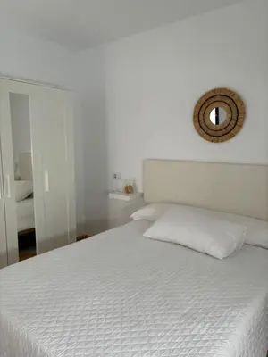 a white bedroom with a white bed with a mirror at Asís 20.7 in Medina Sidonia