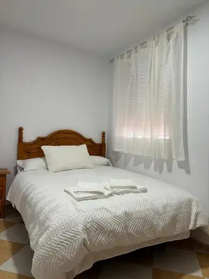 a bedroom with a bed with white sheets and a window at Asís 20.7 in Medina Sidonia