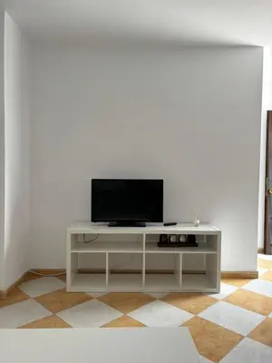a white entertainment center with a television on a white wall at Asís 20.7 in Medina Sidonia