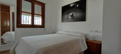 a white bedroom with a bed and a window at Apartamento atico Terraza Centro in El Puerto de Santa María