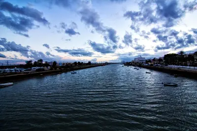 a river with boats in it under a cloudy sky at Apartamento atico Terraza Centro in El Puerto de Santa María