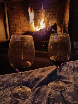 two glasses of wine sitting on a table in front of a fireplace at Villa con piscina in Chiclana de la Frontera