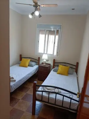 two twin beds in a room with a window at Villa con piscina in Chiclana de la Frontera