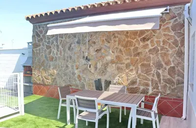 a patio with a table and chairs and a stone wall at Apartamento Rural Marisma in Hozanejos