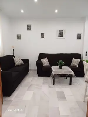a living room with two black couches and a table at Brisas del Guadalquivir in Sanlúcar de Barrameda
