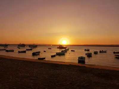a group of boats in the water at sunset at Brisas del Guadalquivir in Sanlúcar de Barrameda
