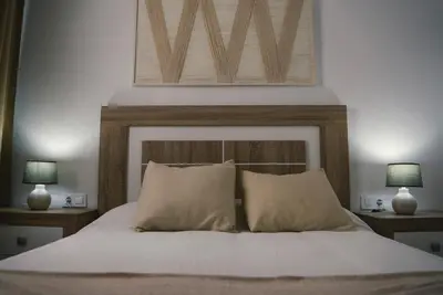 a bed with two pillows and a wooden headboard at Casa Herrete 15 in Medina Sidonia