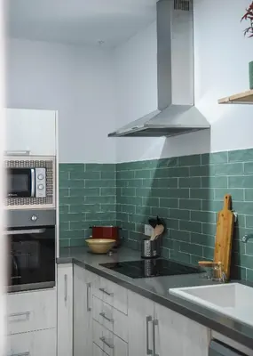 a kitchen with green tiles on the wall at Casa Herrete 15 in Medina Sidonia
