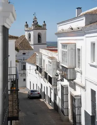 a city street with white buildings and a car at Casa Herrete 15 in Medina Sidonia