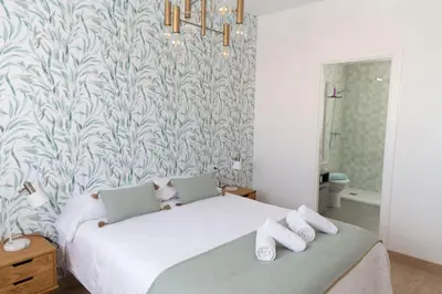 a bedroom with a large white bed with a wallpaper at Las Salinas by Gades Gestión in Puerto Real