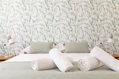 a bed with rolled towels on it with a wallpaper at Las Salinas by Gades Gestión in Puerto Real