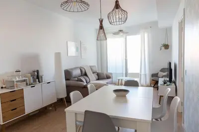 a kitchen and living room with a white table and chairs at Las Salinas by Gades Gestión in Puerto Real