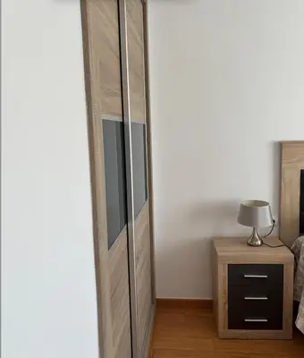 a bedroom with a tall wooden cabinet next to a bed at APARTAMENTO APARTACLUB REFORMADO in Chiclana de la Frontera