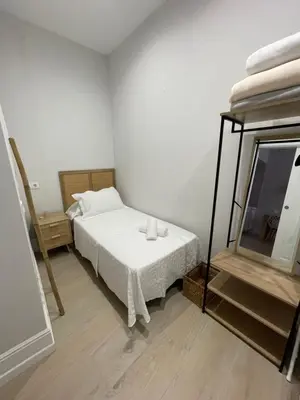 a bedroom with a bed with white sheets and a mirror at Apartamento corredera 1 in Arcos de la Frontera