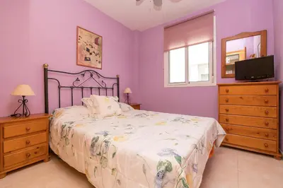a bedroom with a bed and a tv and a window at Rosamar in Chiclana de la Frontera