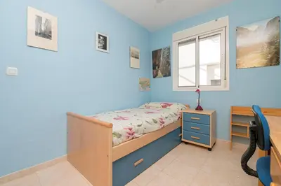 a bedroom with blue walls and a bed and a window at Rosamar in Chiclana de la Frontera
