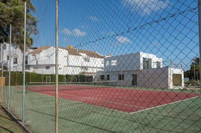 a tennis court with a net in front of a building at Rosamar in Chiclana de la Frontera