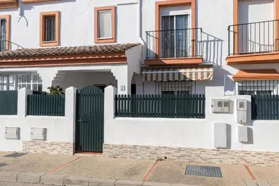a white house with a green gate and balconies at Rosamar in Chiclana de la Frontera