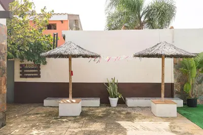 two umbrellas in a courtyard with benches and plants at Casa Amelie in Conil de la Frontera
