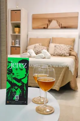 a glass of wine on a table next to a bed at Apartamento Langreo in Jerez de la Frontera