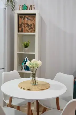 a white dining room table with white chairs and a vase of flowers at Apartamento Langreo in Jerez de la Frontera