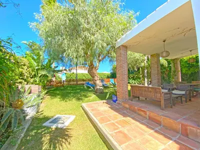 a patio with a bench and a tree at Villa Buganvilla Conil - SOLO FAMILIAS in Conil de la Frontera