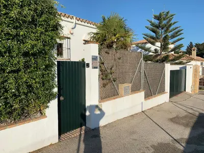 a house with a green gate and a fence at Villa Buganvilla Conil - SOLO FAMILIAS in Conil de la Frontera