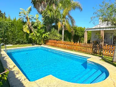 a swimming pool in a yard with a wooden fence at Villa Buganvilla Conil - SOLO FAMILIAS in Conil de la Frontera