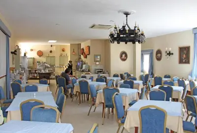 a dining room with tables and chairs and a person at Hotel Al Sur De Chipiona by YouRoom in Chipiona
