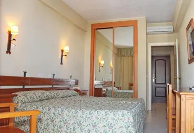 a hotel room with two beds and a mirror at Hotel Al Sur De Chipiona by YouRoom in Chipiona