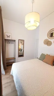a white bedroom with a large bed and a chandelier at Casa Porvenir in Jerez de la Frontera