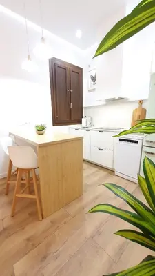 a kitchen with white cabinets and a wooden island at Casa Porvenir in Jerez de la Frontera