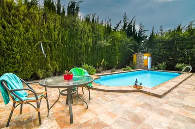 a patio with a table and chairs next to a pool at Villas Dehesa Roche Viejo in Conil de la Frontera