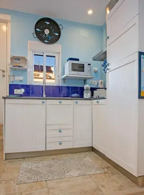 a kitchen with white cabinets and a microwave at Cadizz - El Faro del Manteca - Terraza privada barrio de la Viña - La Caleta in Cádiz