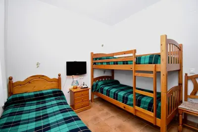 a bedroom with two bunk beds and a television at Recreo de Pilant - Holiday Chiclana in Chiclana de la Frontera