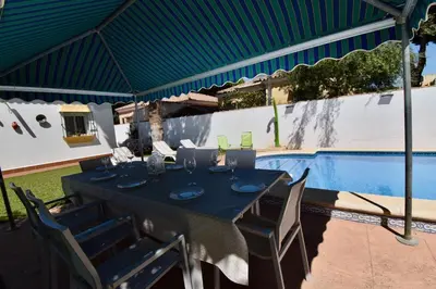 a table and chairs under a tent next to a swimming pool at Recreo de Pilant - Holiday Chiclana in Chiclana de la Frontera