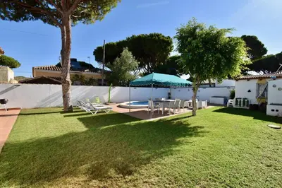a backyard with a table and a blue umbrella at Recreo de Pilant - Holiday Chiclana in Chiclana de la Frontera